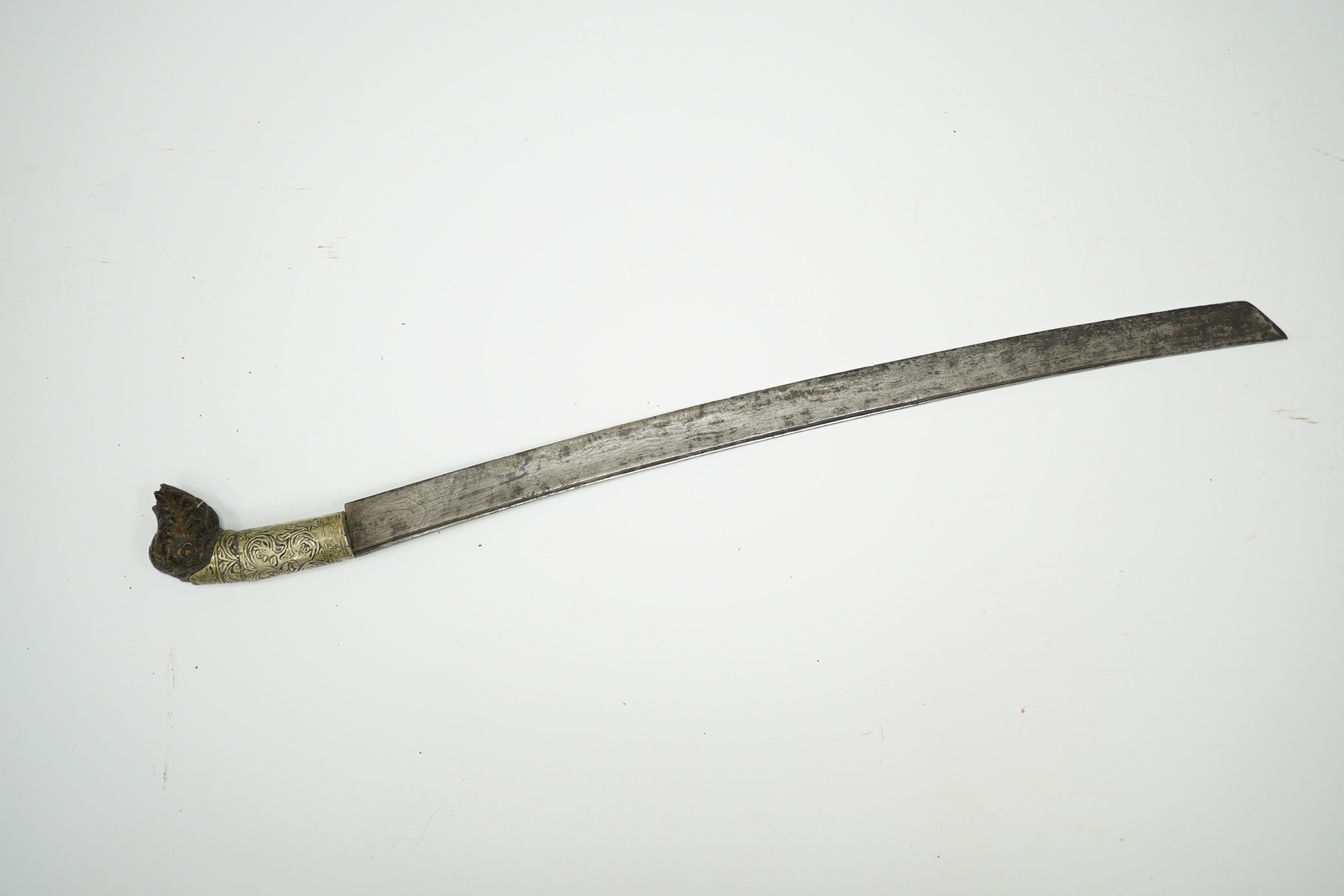 A Malaysian sword Parang, with broad curved pattern welded single edged blade, carved horn pommel, and embossed nickel mounts, in its wooden scabbard. Condition - good